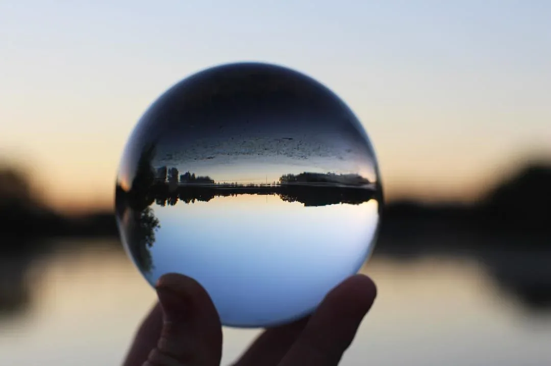 A glass sphere reflecting an inverted landscape at sunset