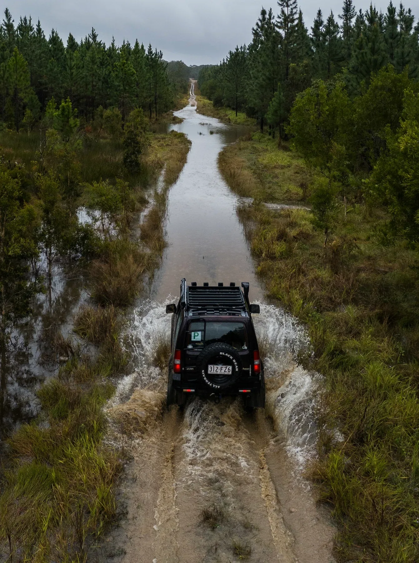 A four-wheel drive splashing along a flooded forest track